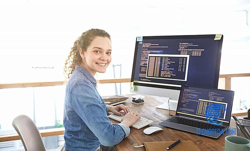 Mujer trabajando con ordenador y sonriendo a cámara