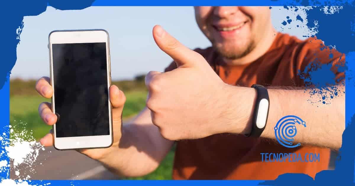 Hombre mostrando la pulsera fitbit y el móvil
